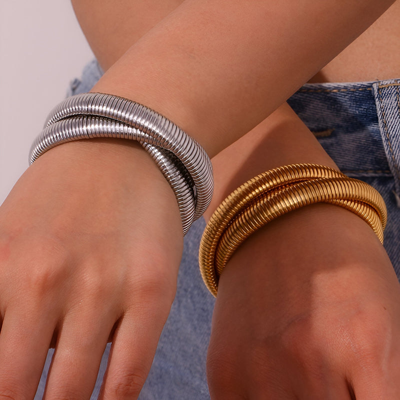 Ensemble de trois bracelets manchettes métalliques, finitions argent et or, design contemporain.