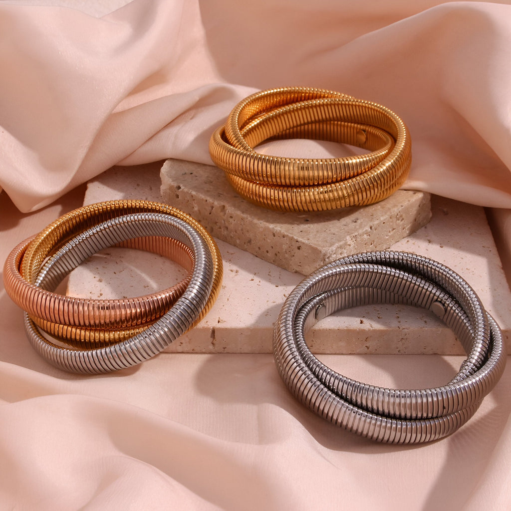 Ensemble trio de bracelets manchettes Oriane en métal doré, argenté et bicolore cuivre et argent posé sur blocs en pierre.