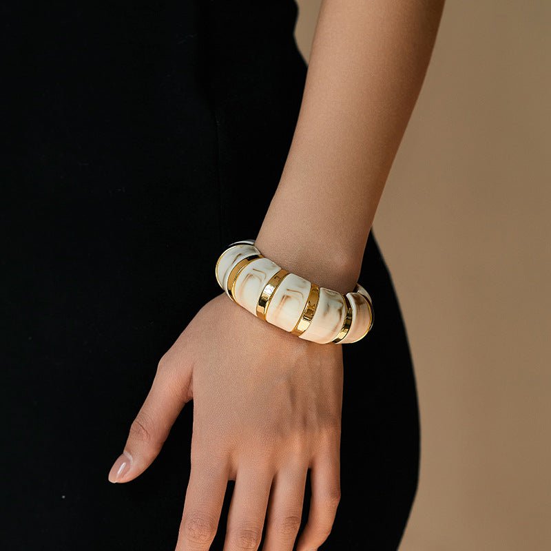 Bracelet manchette épais en acrylique blanc avec détails dorés, style chic pour femme.