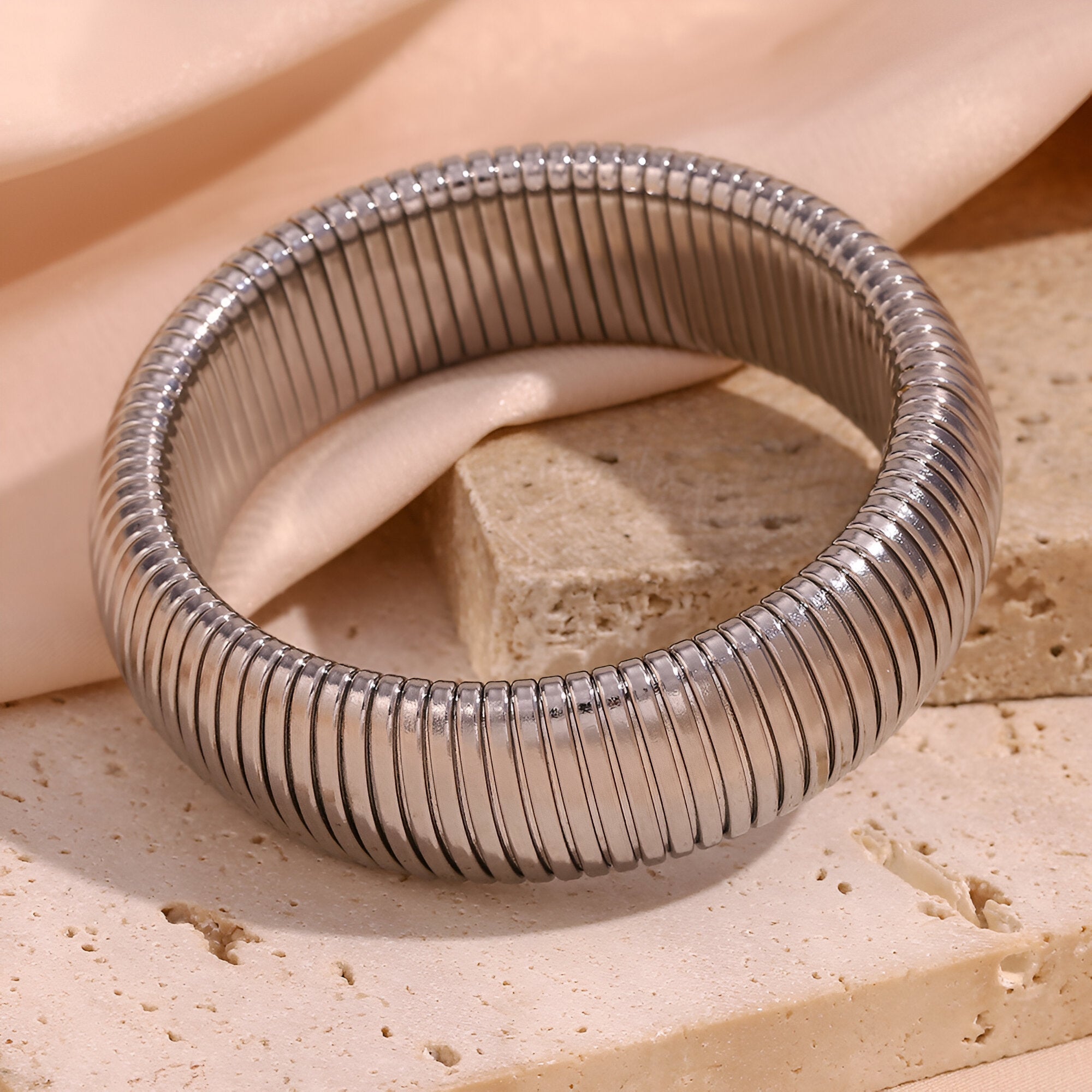 Bracelet manchette flexible en maille argentée, design épuré et moderne.