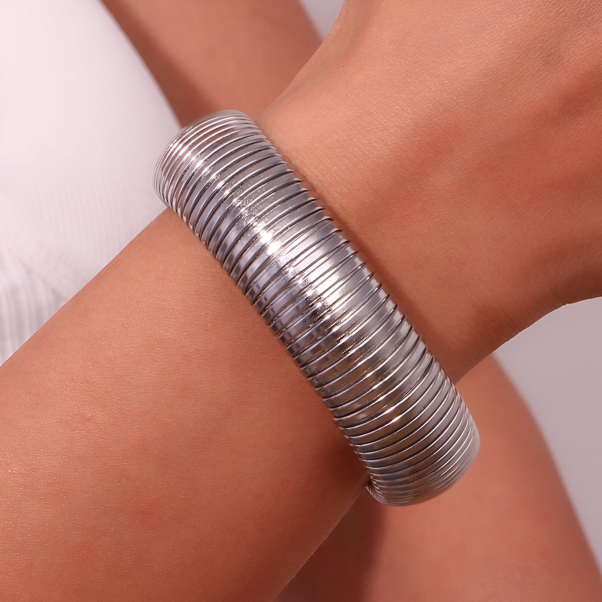 Bracelet manchette flexible en maille argentée, design moderne et élégant.