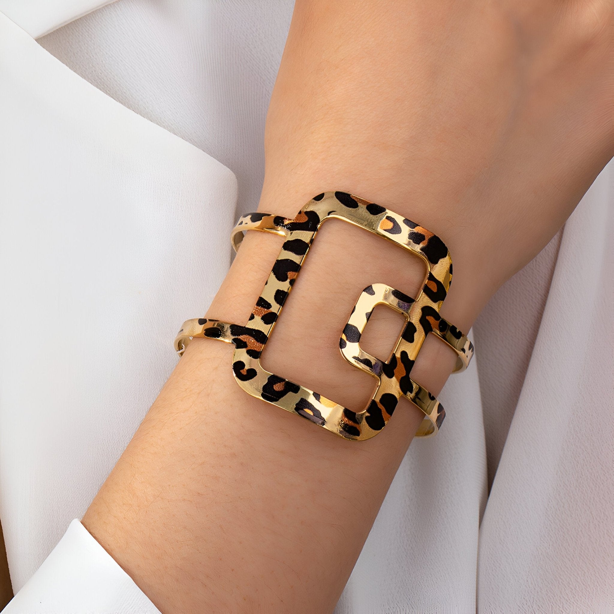 Bracelet manchette en métal doré motif léopard avec forme géométrique élégante sur poignet féminin.