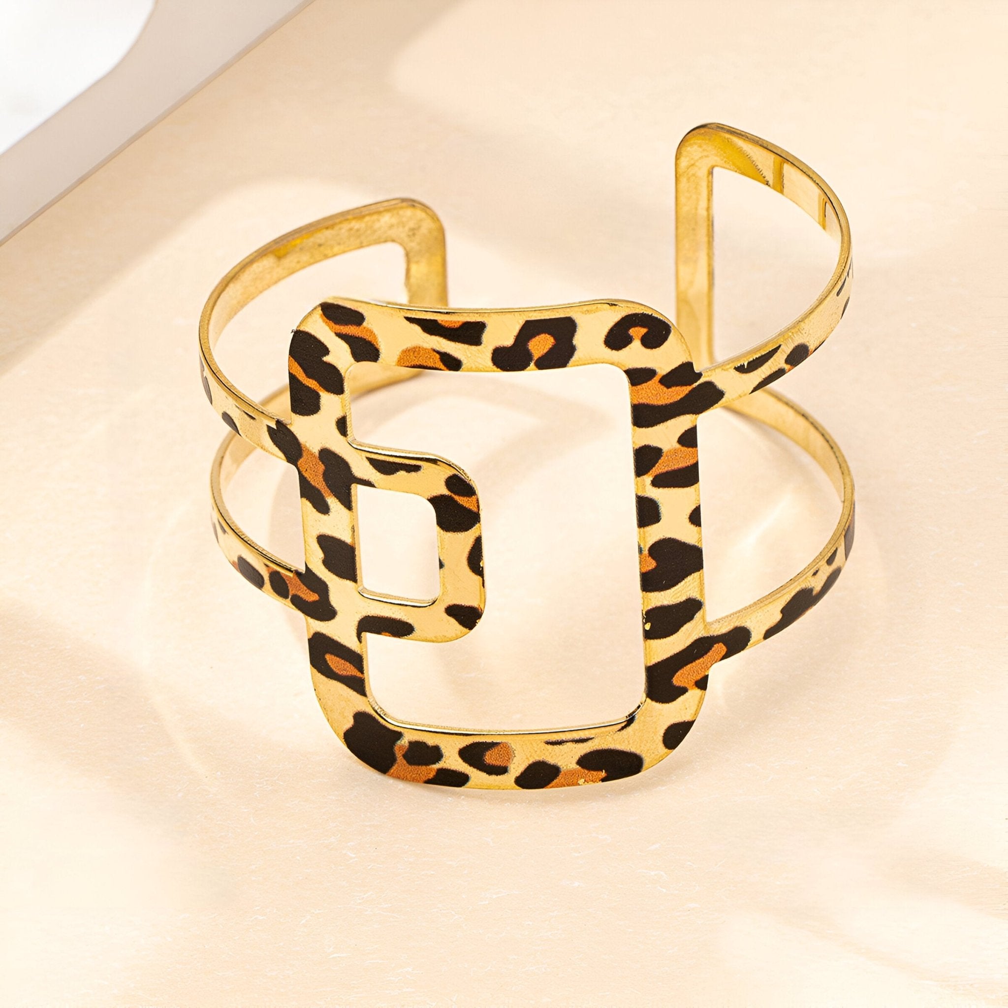 Bracelet manchette doré en métal or avec motif léopard et forme géométrique ajourée.