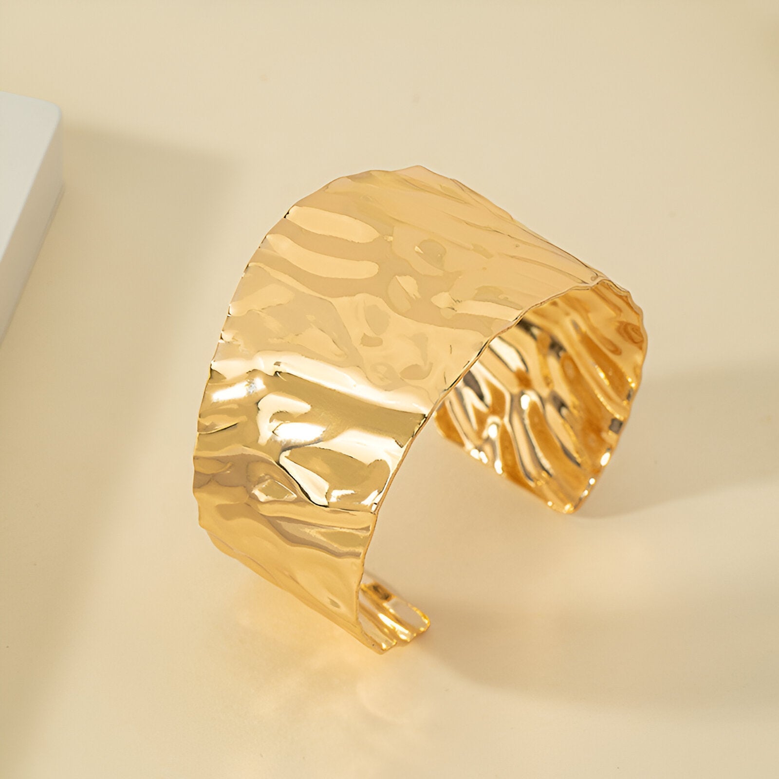Bracelet manchette ondulé en alliage métallique doré brillant au design large et texturé.
