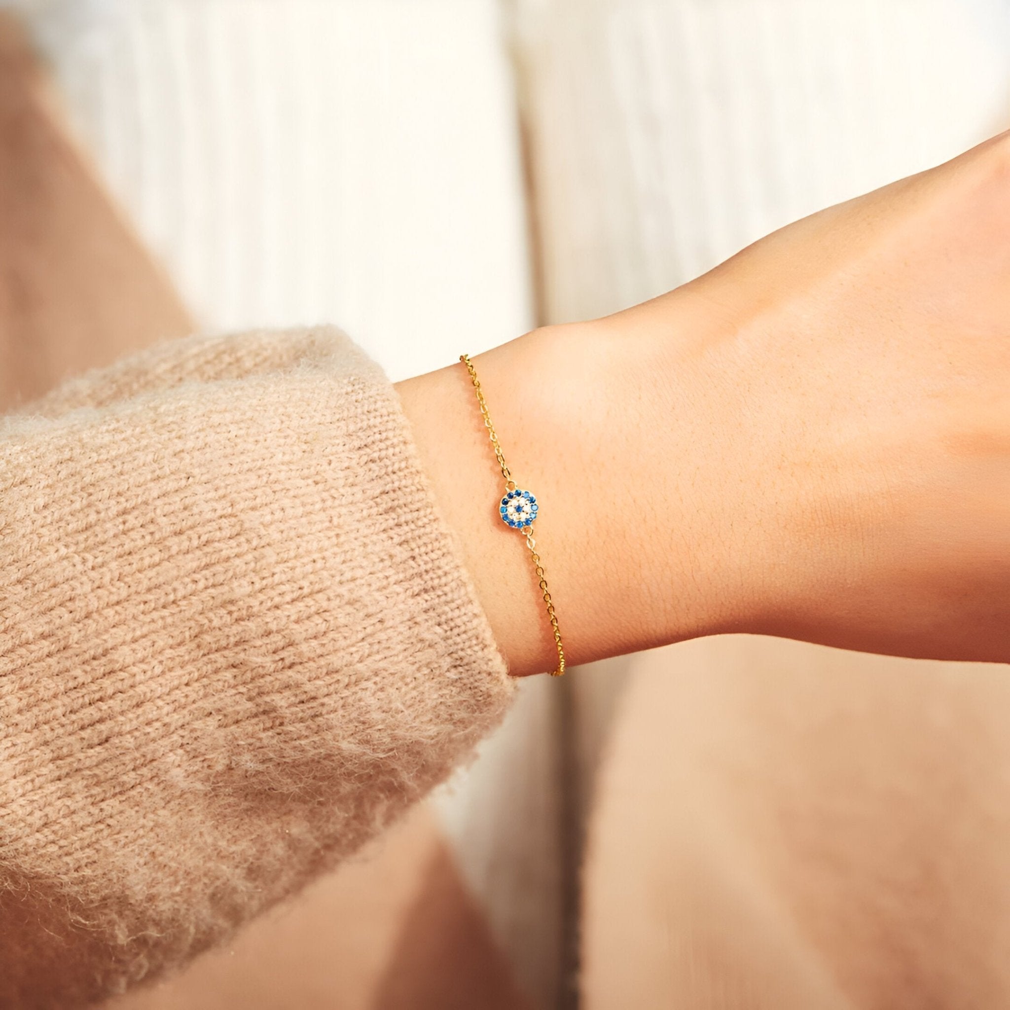 Bracelet fin en argent sterling avec pendentif œil bleu et blanc porté au poignet féminin.