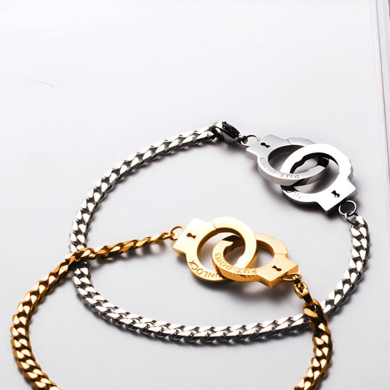 Bracelet menottes en acier inoxydable, chaîne argentée et or avec fermoirs menottes entrelacées.