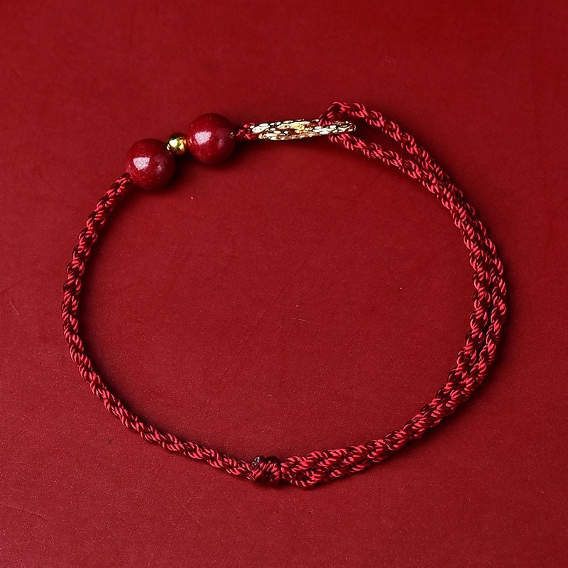 Bracelet fin en fil ciré bordeaux avec breloques en pierre de cinabre et motif infini doré.