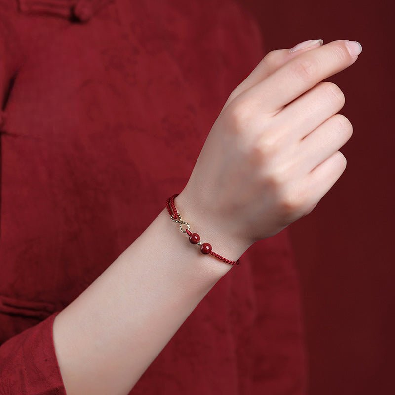 Bracelet fin en fil rouge ciré avec pierres de cinabre et petit motif infini argenté.