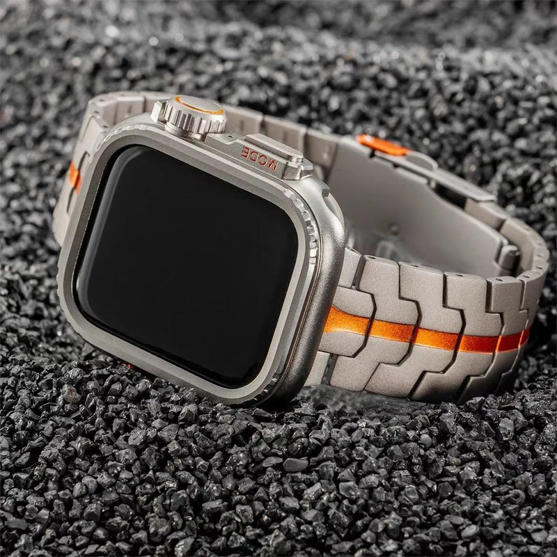Bracelet montre Apple en titane gris avec maille robuste et ligne orange centrale, boucle déployante robuste.