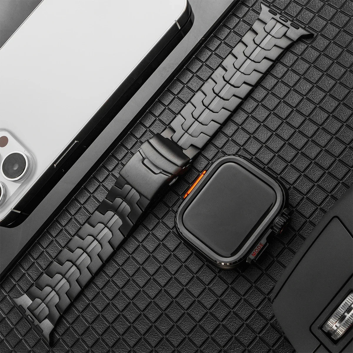 Bracelet montre Apple en titane gris anthracite, maille moderne robuste avec ligne orange distinctive et boucle déployante.