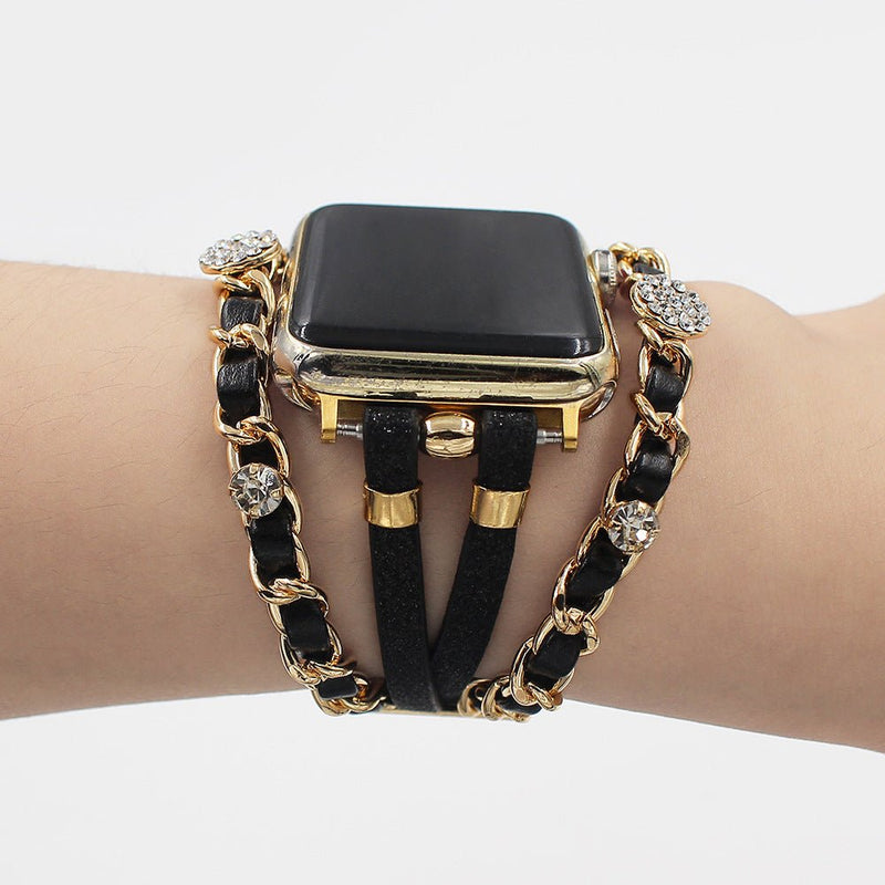 Bracelet montre Apple Watch simili cuir noir avec chaîne dorée et strass brillants, style double tour élégant.