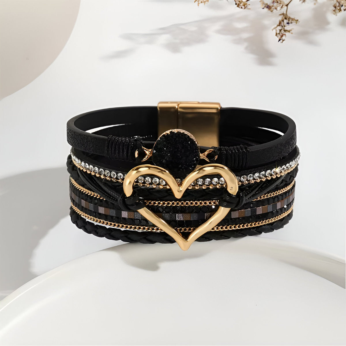 Bracelet multi-rangs noir avec grand cœur doré central et détails brillants, fermeture magnétique dorée.