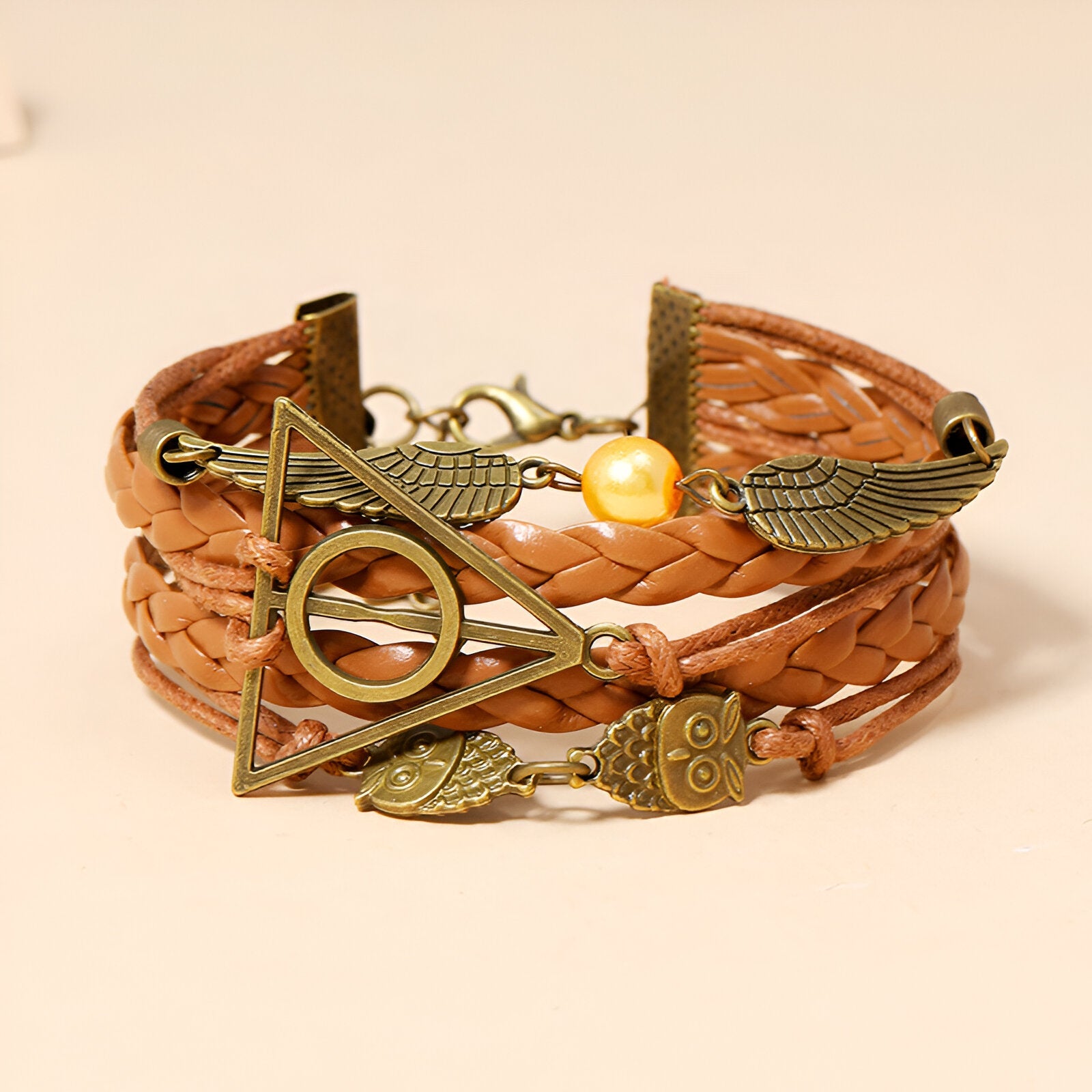 Bracelet multi-rangs en cuir marron tressé avec breloques ailes d'ange, hiboux et plumes dorées, perle nacrée centrale.