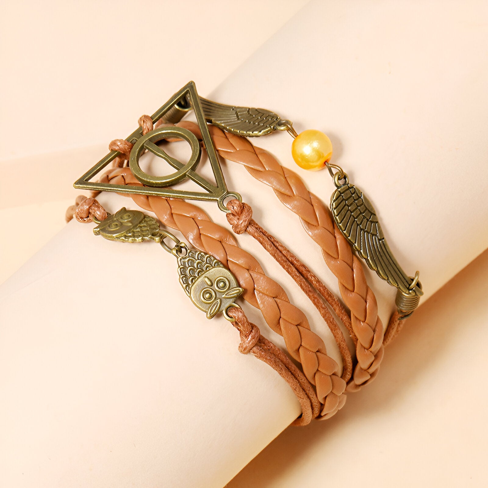 Bracelet multi-rangs marron avec breloques en métal doré ailes d'ange, hiboux et perle jaune.