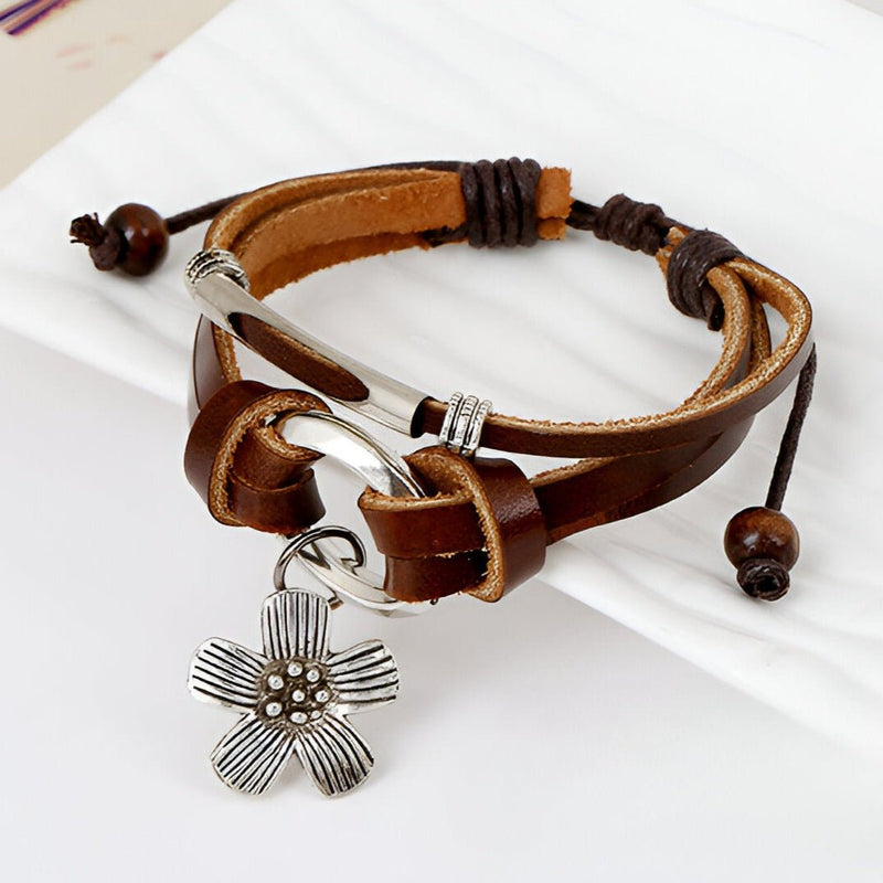 Bracelet multi-rangs en cuir marron avec charm fleur en métal argenté et cordon réglable à perles en bois.