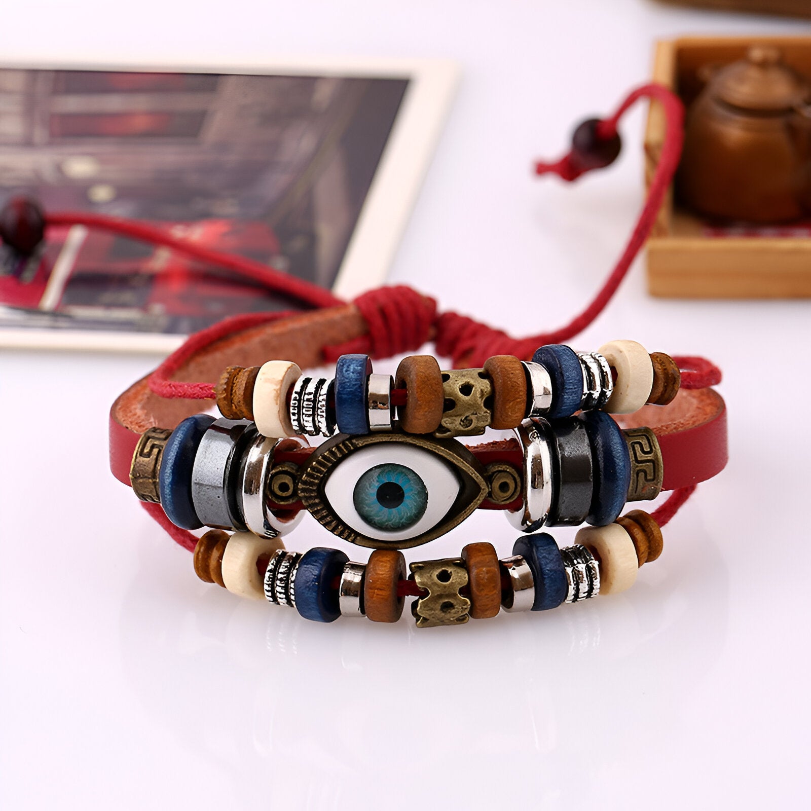 Bracelet multi-rangs en cuir rouge avec perles bleues, blanches, marron, et œil de protection central en céramique.