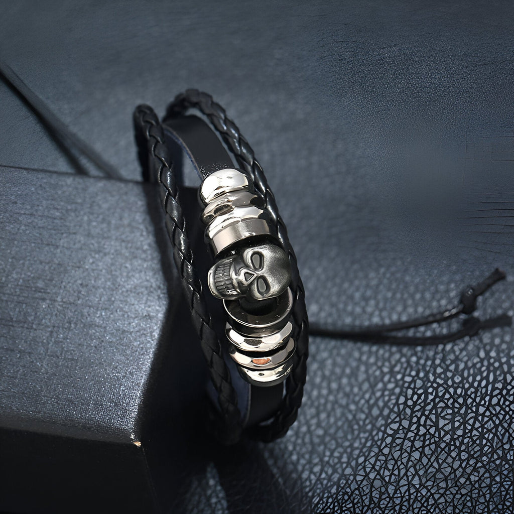 Bracelet multi-rangs en cuir noir avec tête de mort en métal argenté et détails ronds métalliques.