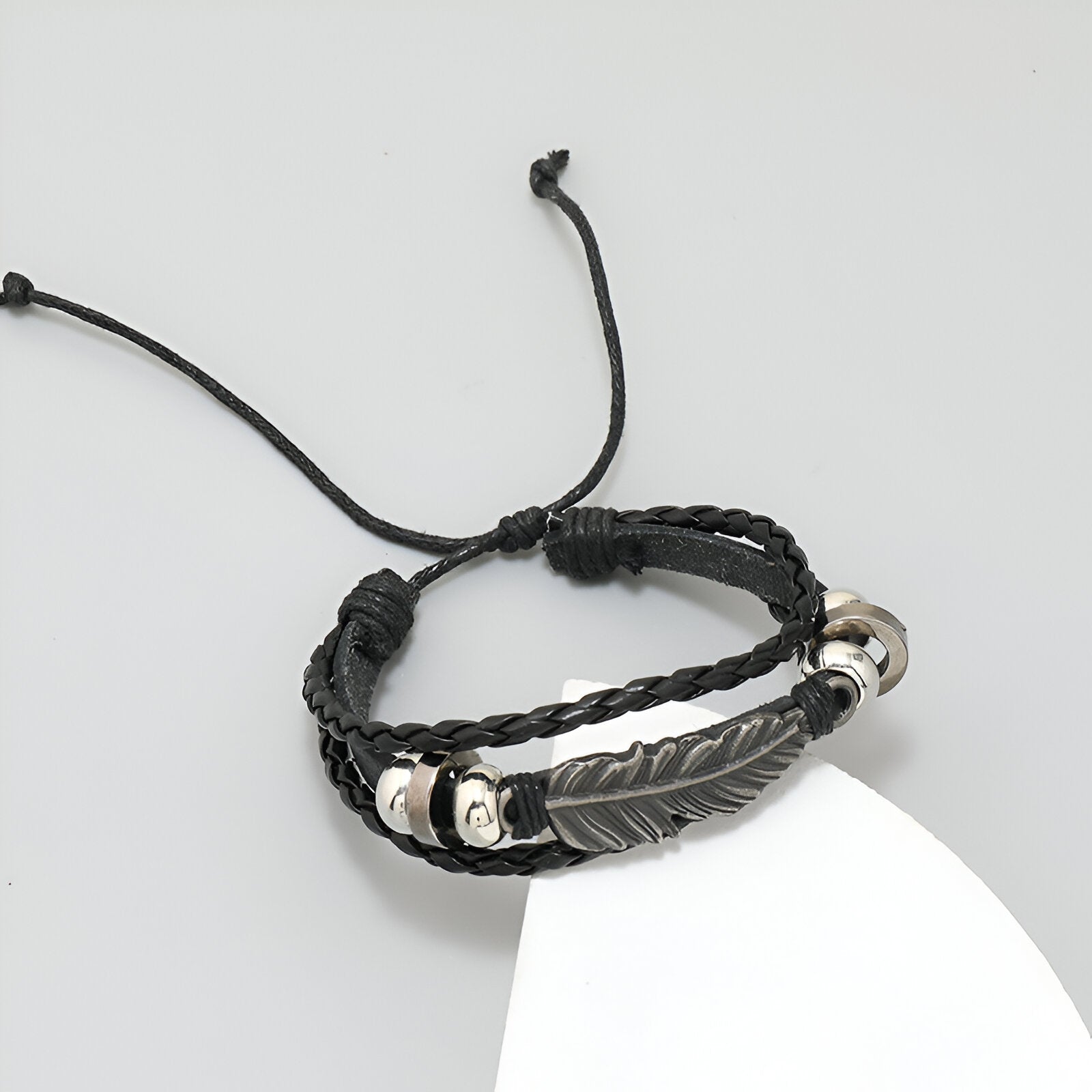 Bracelet multi-rangs noir en microfibre avec grande plume métallique argentée et perles décoratives.