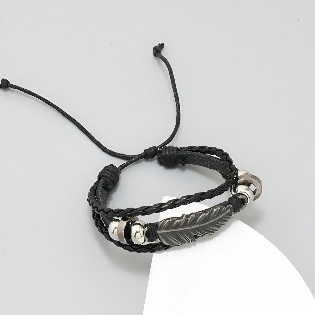 Bracelet multi-rangs noir en microfibre avec grande plume métallique argentée et perles décoratives.