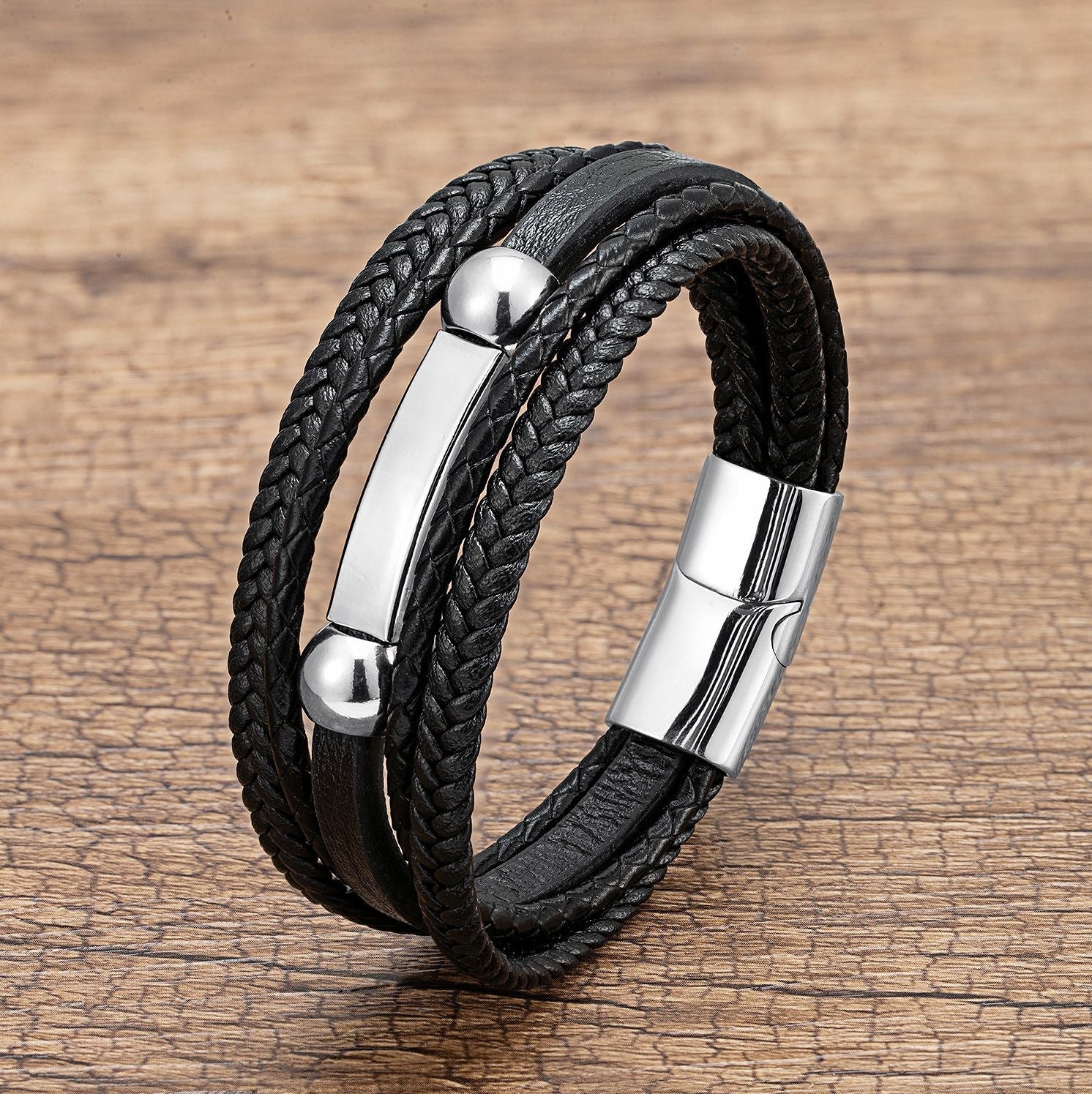 Bracelet multi-rangs noir en microfibre tressée avec détails métalliques argentés, fermoir magnétique.