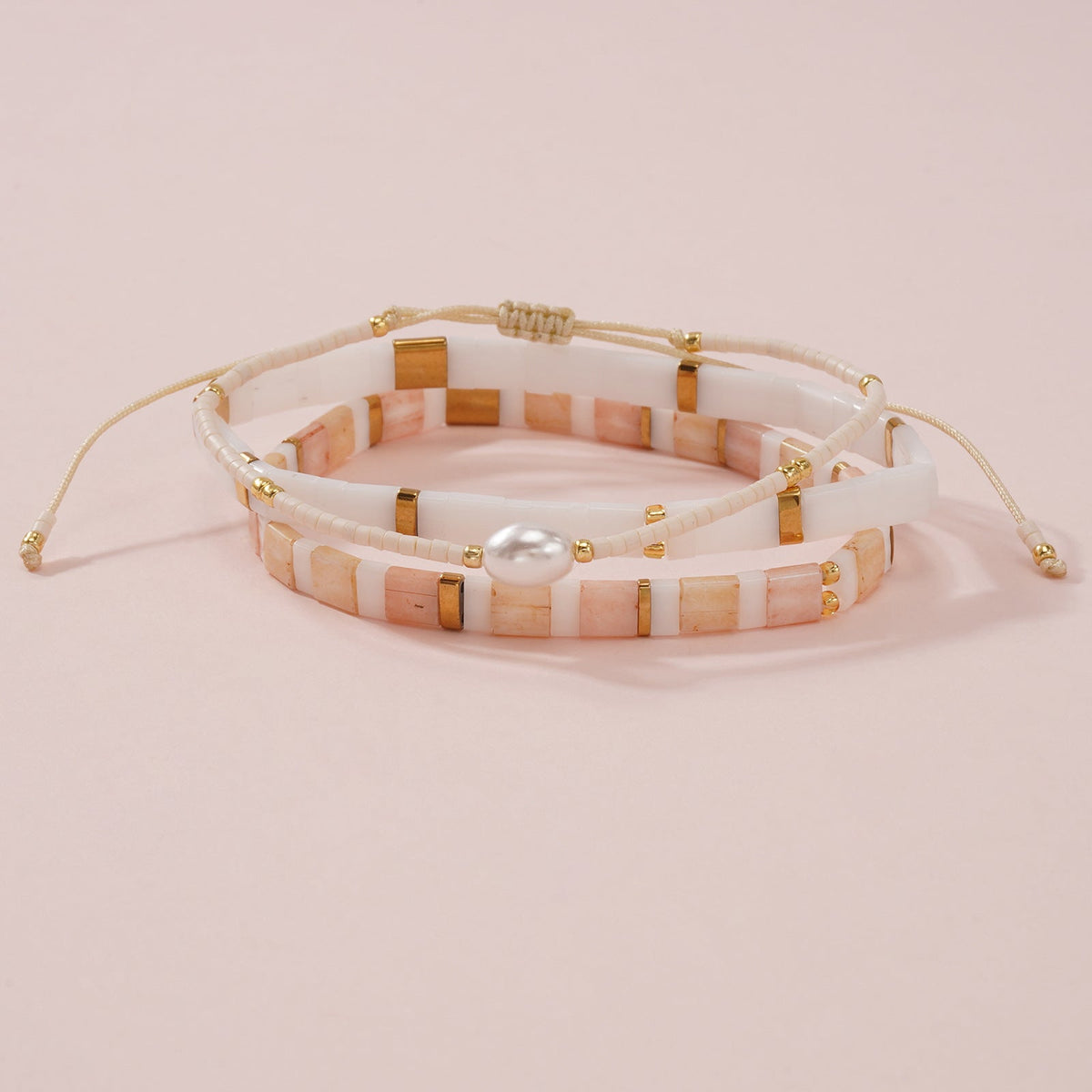 Bracelet multi-rangs perles japonaises crème et rose avec perle coquillage centrale et détails dorés, fermoir ajustable.