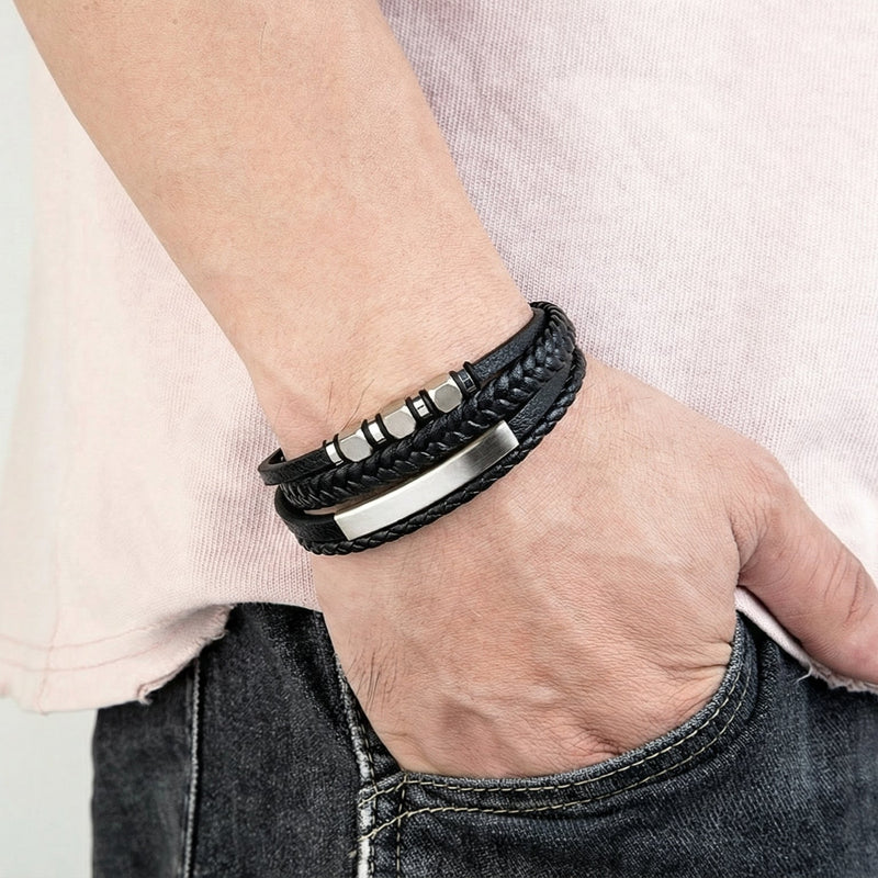 Bracelet multi-rangs homme en cuir noir avec éléments géométriques métalliques argentés et fermoir magnétique élégant.