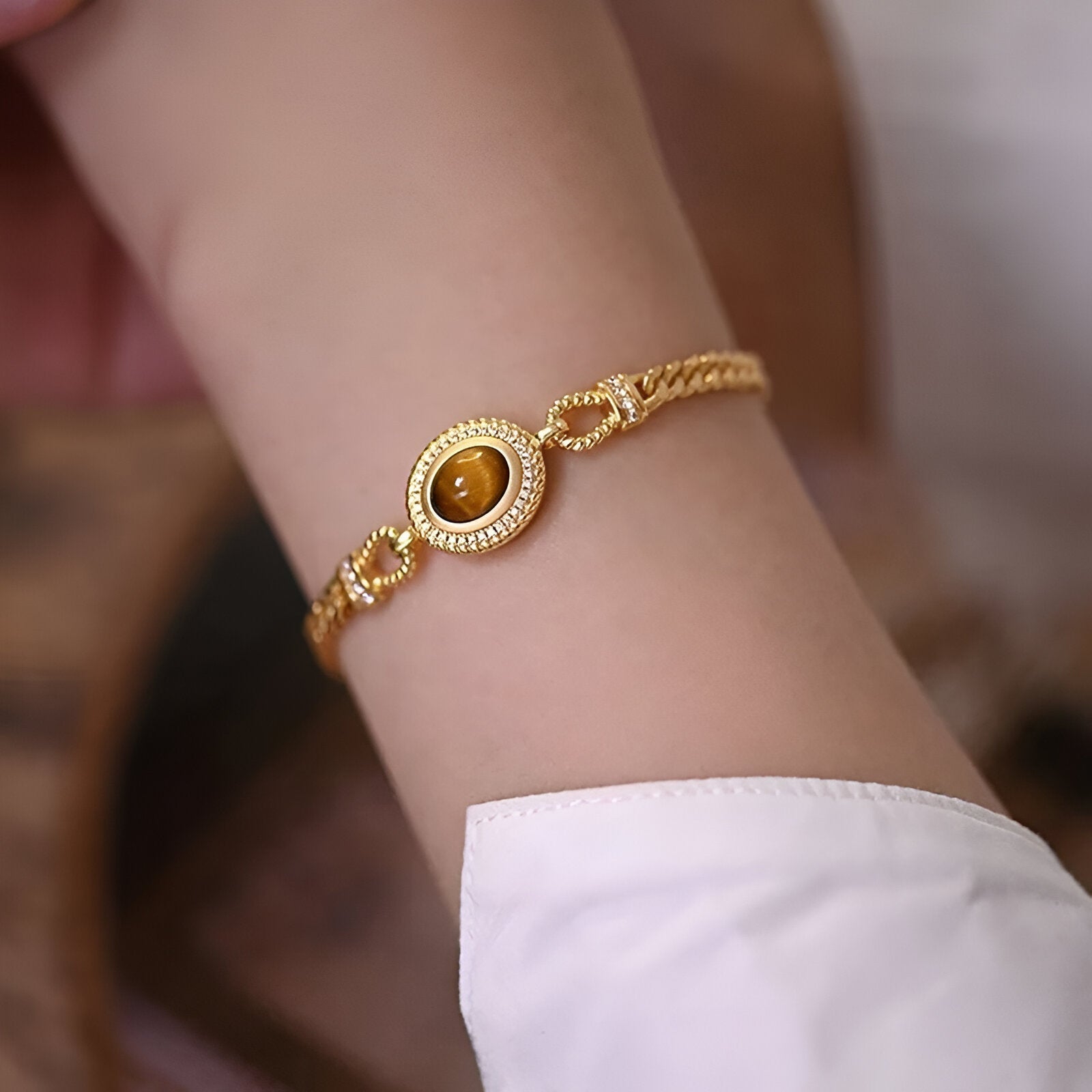 Bracelet en acier inoxydable doré avec pierre œil de tigre ovale et maillons décoratifs fins.