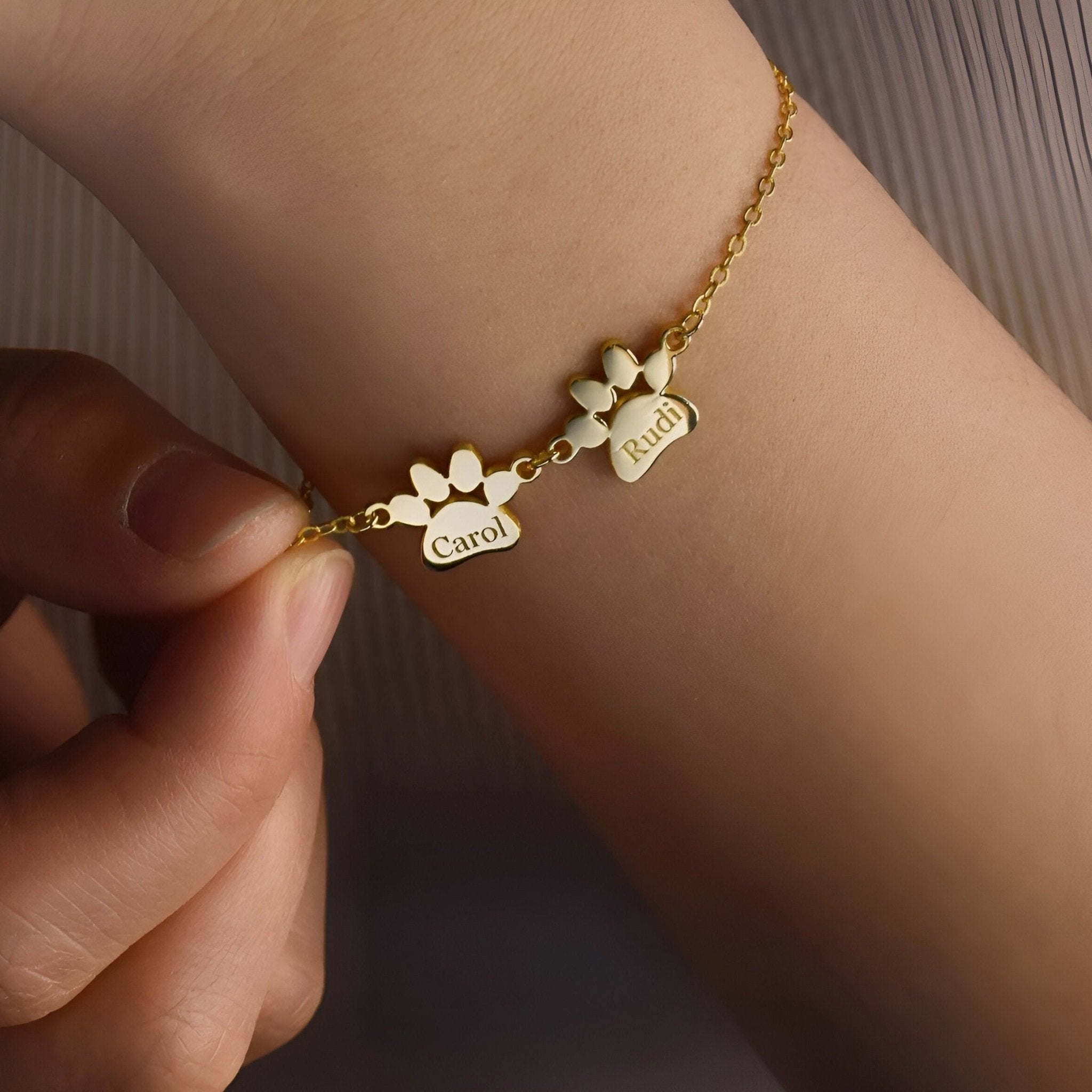 Bracelet en acier inoxydable doré avec deux pendentifs pattes gravés "Carol" et "Paul".