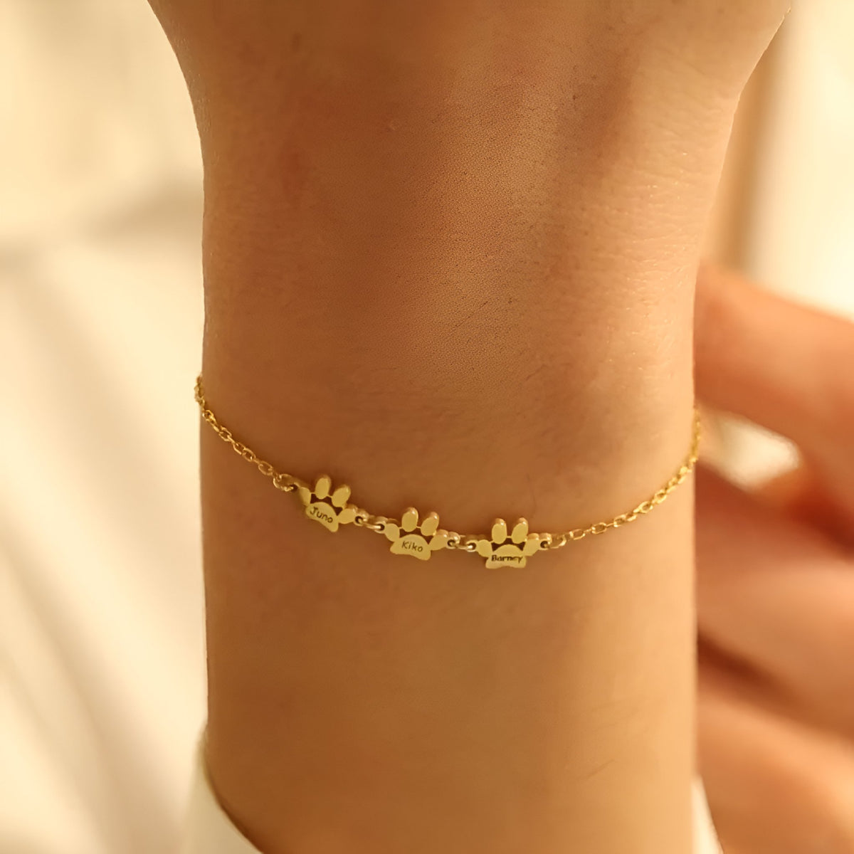 Bracelet fin en acier inoxydable doré avec trois pendentifs pattes délicats sur chaîne ajustable.