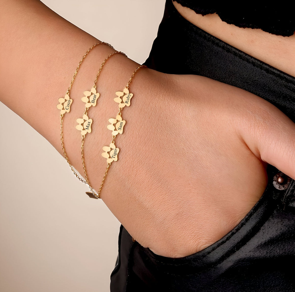 Bracelet fin or avec pendentifs patte de chat en acier inoxydable porté au poignet.