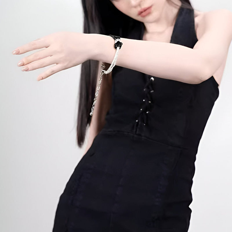 Bracelet perlé blanc avec nœud central noir porté sur poignet féminin, style élégant et minimaliste.