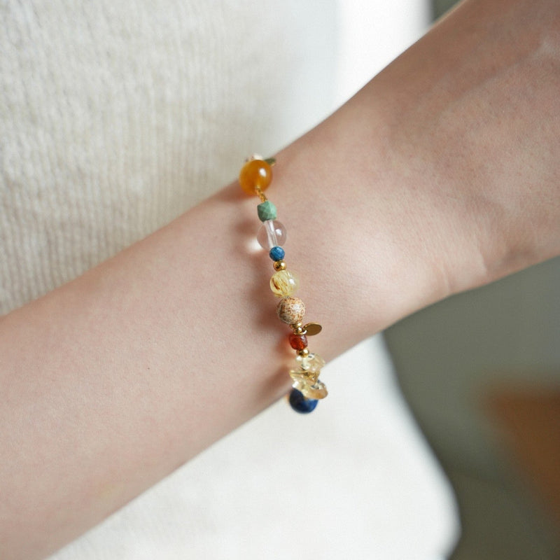 Bracelet perlé avec pierres naturelles multicolores et éclats dorés sur poignet, design élégant et fin.