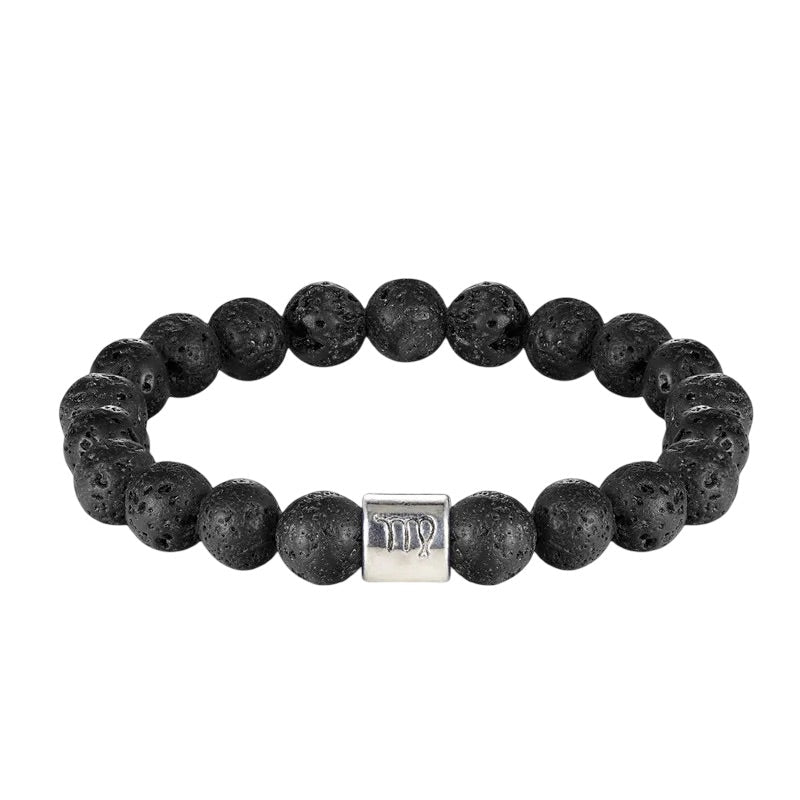 Bracelet élastique en perles de pierre de lave noires avec un cylindre argenté gravé de symboles astrologiques.