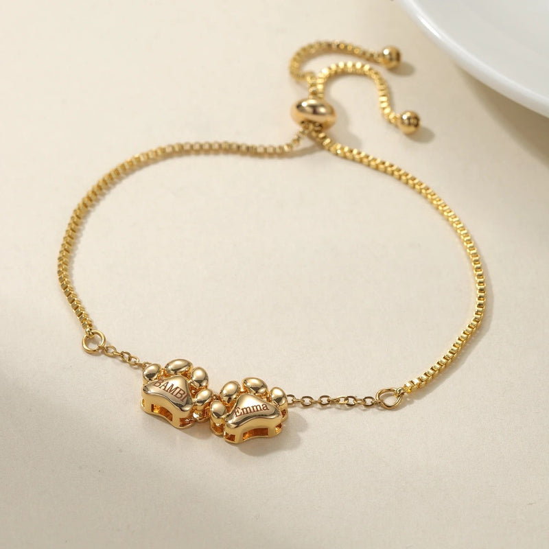 Bracelet personnalisé doré en acier inoxydable avec pendentifs pattes entrelacées et chaîne réglable.