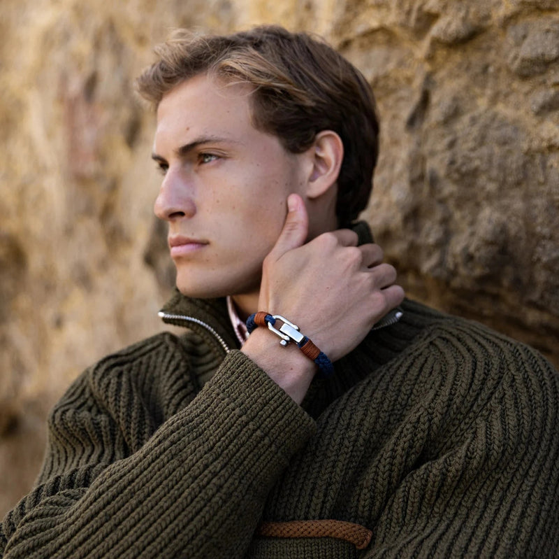 Bracelet bleu à mousqueton pour homme en corde tressée avec détails métalliques, porté au poignet.