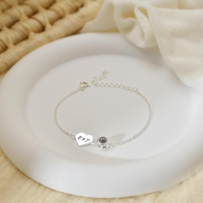 Bracelet fin en acier inoxydable avec pendentif cœur gravé et médaille ronde noire, style délicat et élégant.