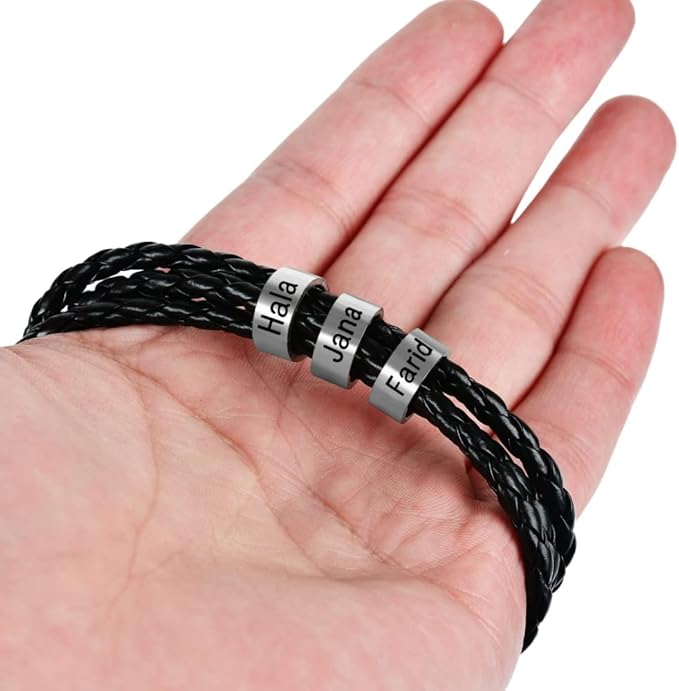 Bracelet en cuir noir triple tour tressé avec trois anneaux métalliques gravés sur main ouverte.