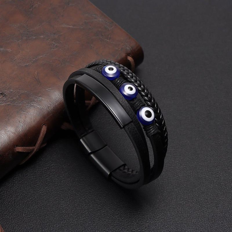 Bracelet multi-rangs en cuir noir avec trois yeux protecteurs bleus et fermoir magnétique noir mat.