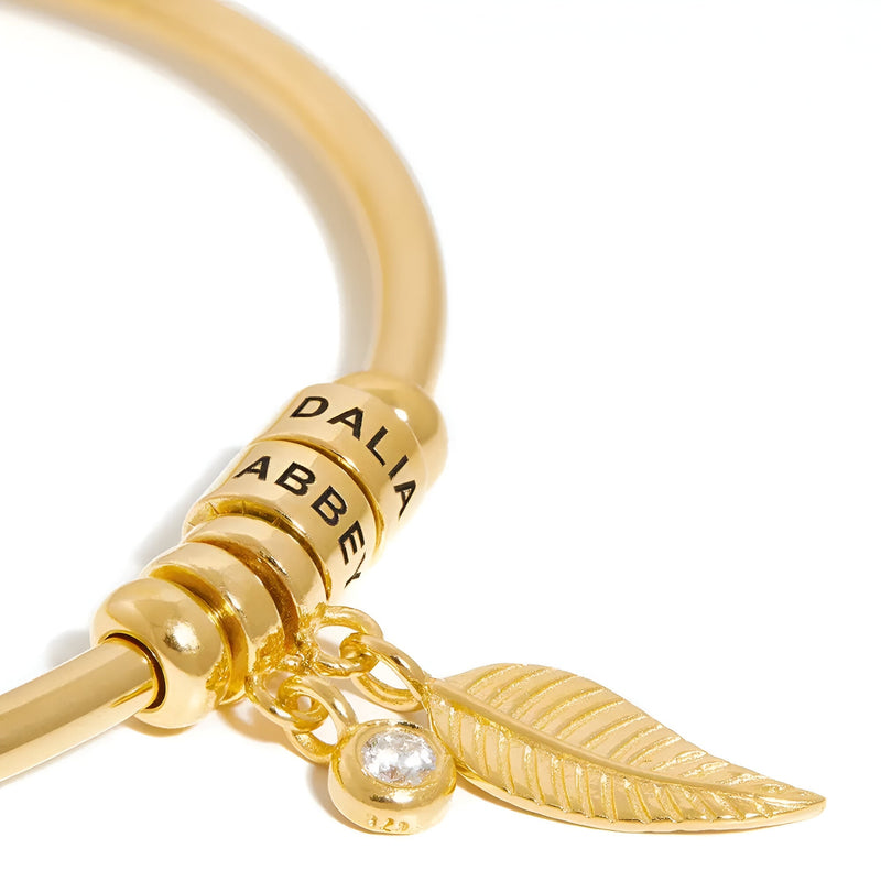 Bracelet doré en acier inoxydable avec deux anneaux personnalisés, breloques feuille et pierre brillante.