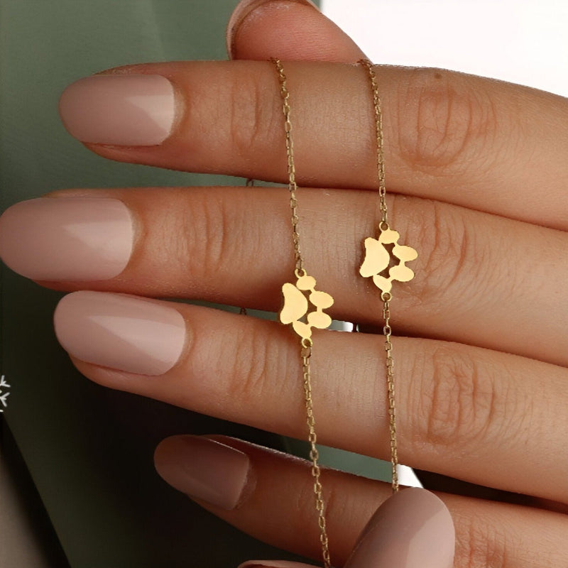 Bracelet or fin en acier inoxydable avec pendentif patte de chien délicat sur chaîne fine.