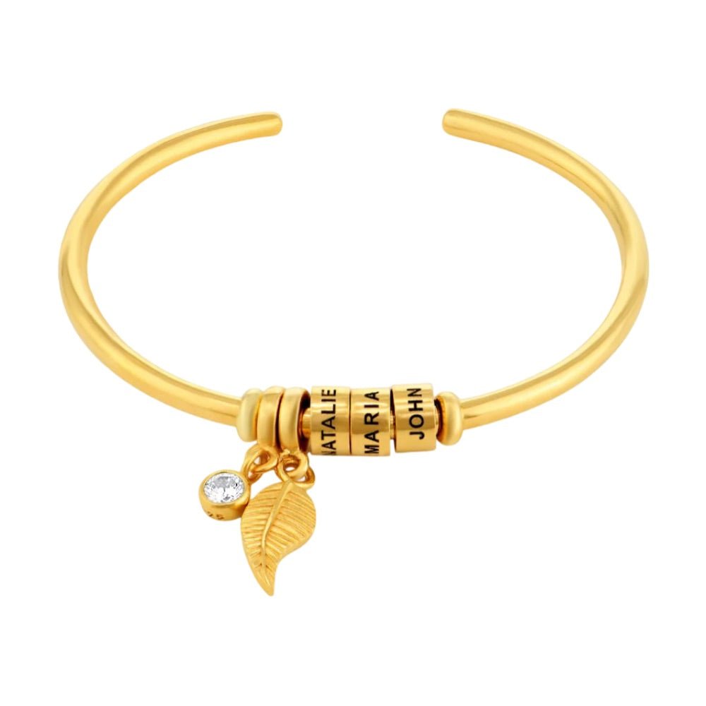 Bracelet ouvert en acier inoxydable doré avec trois anneaux personnalisables et pendentifs feuille et pierre brillante.