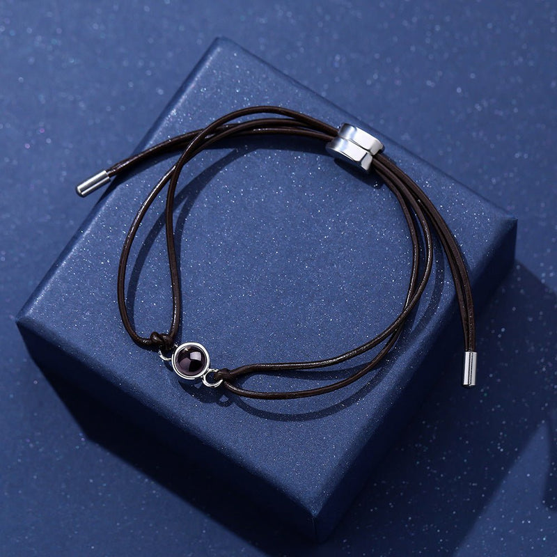 Bracelet à cordon réglable en cuir marron avec pendentif rond argenté à image cachée.