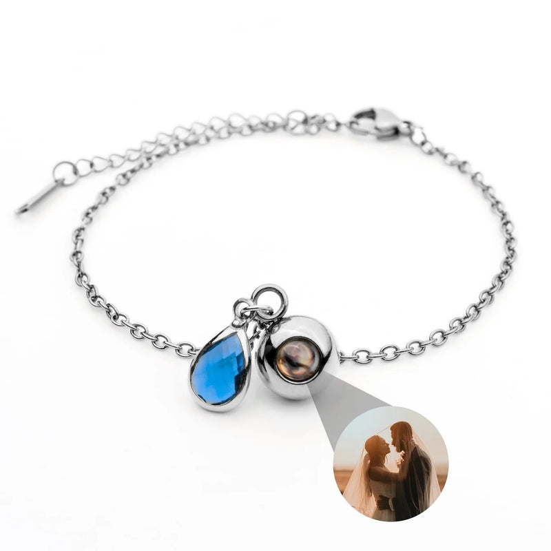 Bracelet en acier inoxydable avec photo personnalisée ronde et pierre de naissance bleue en forme de goutte.