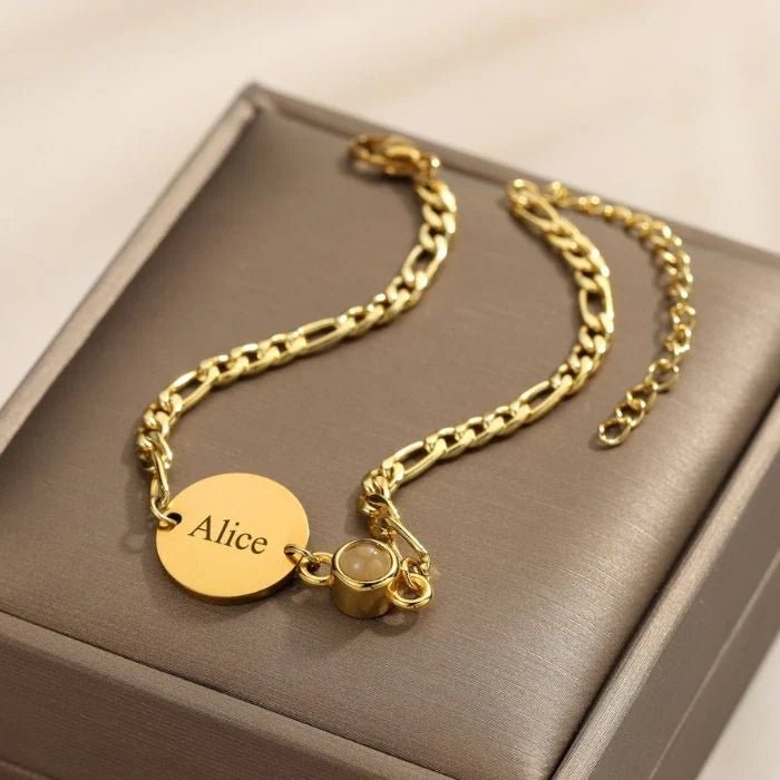 Bracelet doré à maillons Figaro avec médaille ronde gravée du prénom Alice, fermoir rond, présenté sur coffret gris.