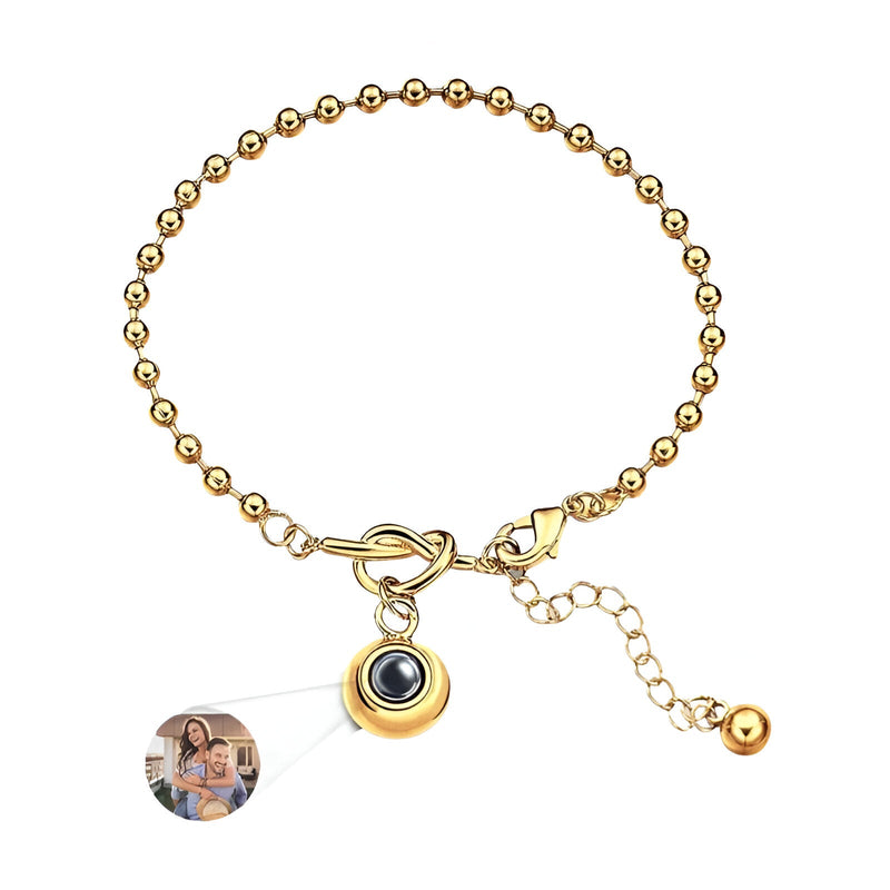 Bracelet femme en acier inoxydable doré à billes avec pendentif photo à nœud central et chaîne réglable.