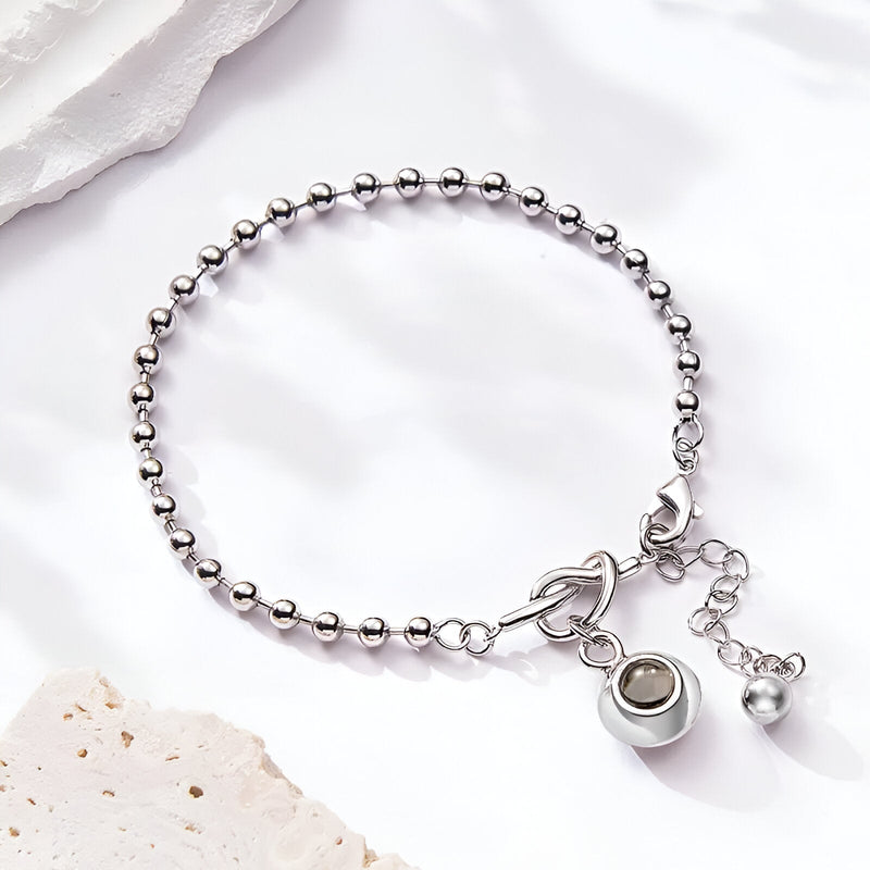 Bracelet en acier inoxydable argenté avec nœud central et pendentif photo rond personnalisable.
