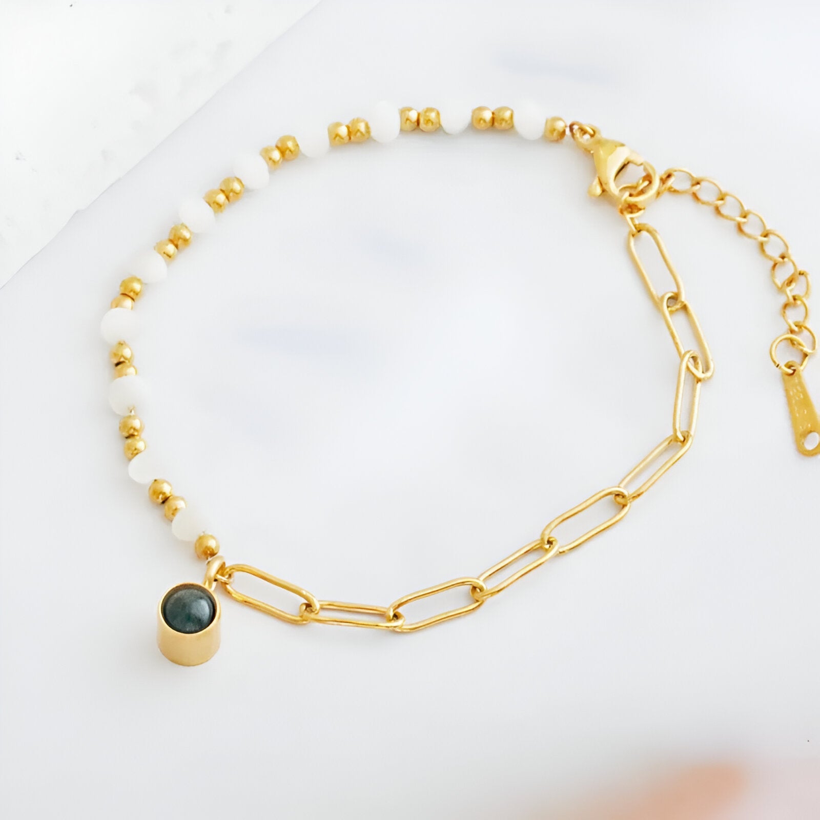 Bracelet en acier inoxydable doré avec perles d'eau douce et pendentif rond noir élégant.