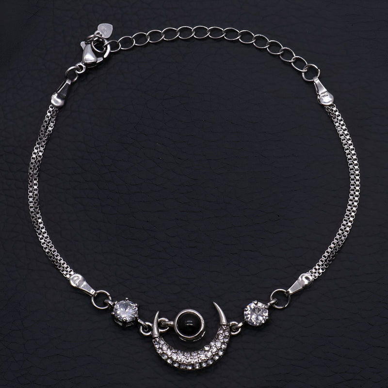 Bracelet en argent sterling avec pendentif lune orné de petits cristaux et deux pierres brillantes de chaque côté.