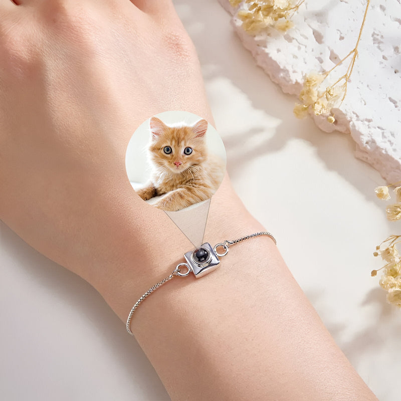 Bracelet photo personnalisé en titane avec charm carré argenté et chaîne fine sur poignet féminin.