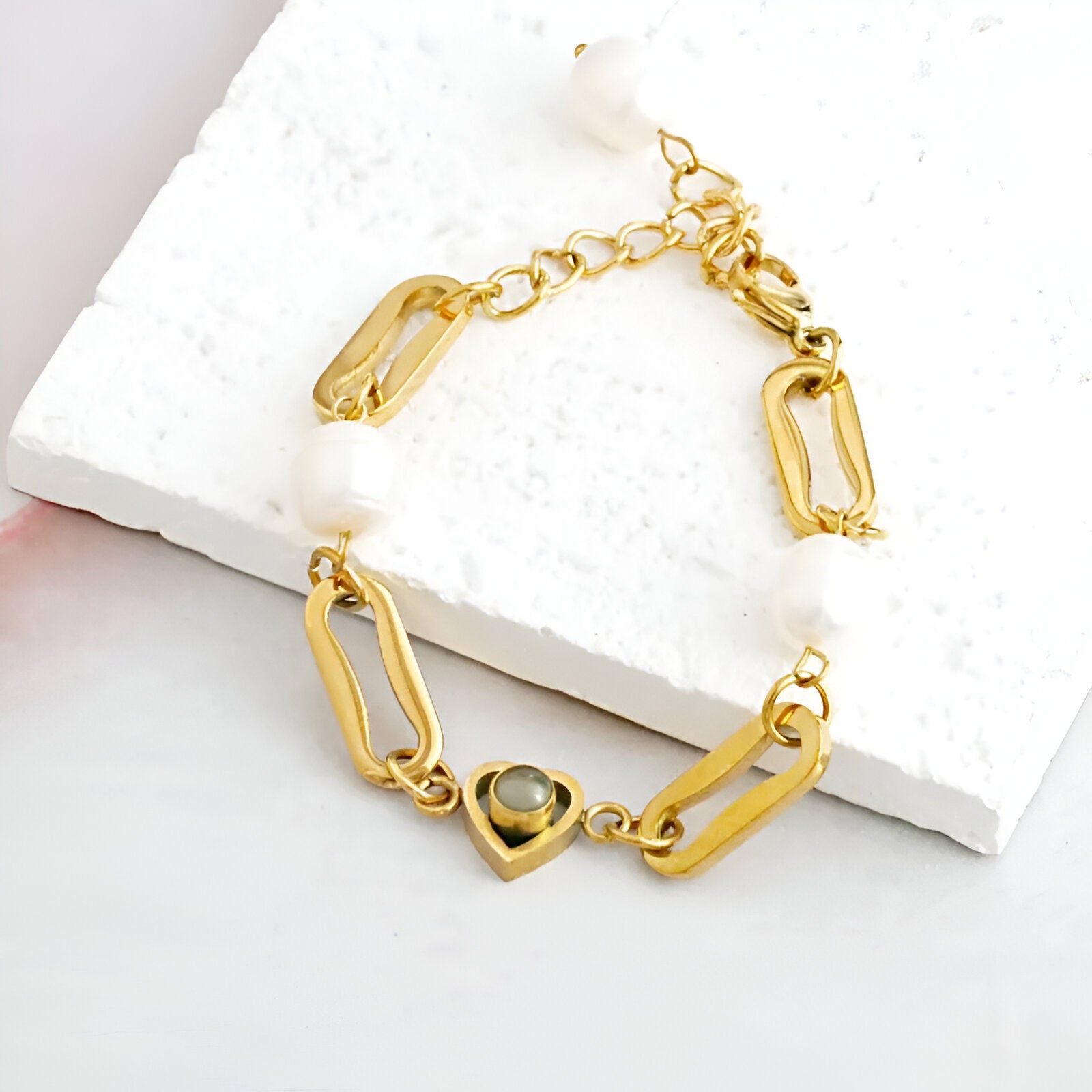 Bracelet en titane doré avec perles d'eau douce et pendentif cœur orné d’une pierre noire.